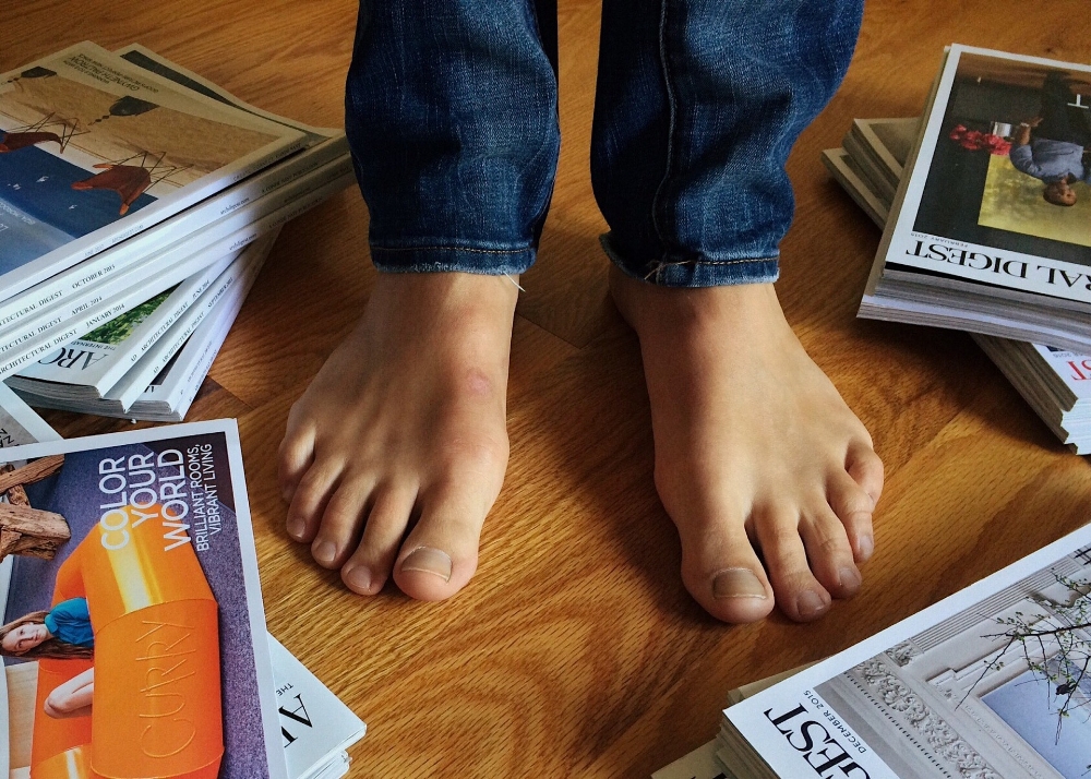 Bare feet surrounded by magazines. Photo by Wokandpix.